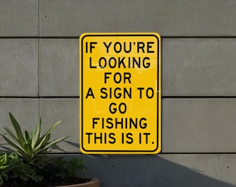 May include: A yellow sign with black text that reads "If you're looking for a sign to go fishing this is it."