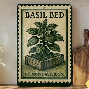 May include: A rectangular metal sign with a vintage design, featuring the words "BASIL BED" and "OCIMUM BASILICUM." The sign depicts a detailed illustration of a basil plant in a wooden planter. The sign has a green border and is mounted on a wall.