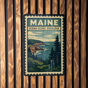 A framed poster of Maine's Ocean Scenic overlook is displayed on a wooden wall.
