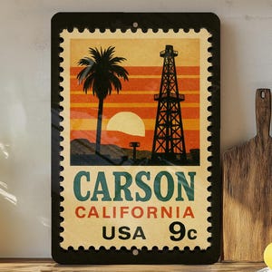 May include: A rectangular metal sign featuring a vintage-style design of a California landscape. The image includes a palm tree, oil derrick, and a setting sun. Text on the sign reads "CARSON CALIFORNIA USA 9c". The sign has a black border with a postage stamp design.