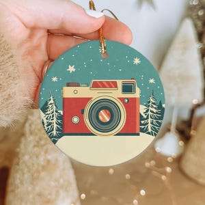 a person holding a christmas ornament with a camera on it