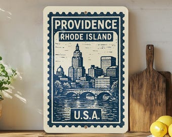 May include: A rectangular sign featuring a blue and white illustration of the Providence, Rhode Island skyline. The sign has a postage stamp design with the words "PROVIDENCE RHODE ISLAND" and "U.S.A." printed on it. The sign is displayed on a wooden surface.