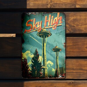 May include: A vintage-style metal sign with a blue background and the text "Sky High" in red and yellow lettering. The sign features a depiction of the Space Needle in Seattle, Washington.