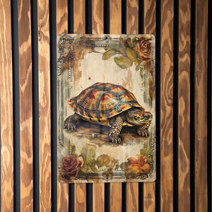 May include: A vintage-style metal sign featuring a detailed illustration of a turtle with a brown and yellow shell. The turtle is surrounded by floral designs and a decorative frame.