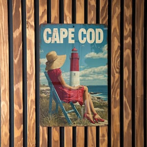 May include: A vintage metal sign with the words "CAPE COD" in white lettering. The sign depicts a person in a red dress and straw hat sitting in a blue chair, overlooking the ocean and a red and white lighthouse.