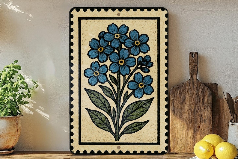 a decorative tile with a blue flower design, placed on a wooden surface next to a wooden cutting board and a potted plant.