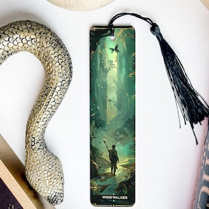 May include: A green and gold bookmark with a fantasy illustration of a person walking through a forest. The bookmark has a black tassel and the text "WIND WALKER" at the bottom.