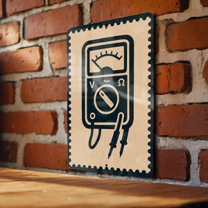 May include: A vintage-style metal sign featuring a black and white illustration of a multimeter. The sign has a beige background with a black border and is mounted on a brick wall. The multimeter graphic includes a dial, voltage, and resistance symbols.