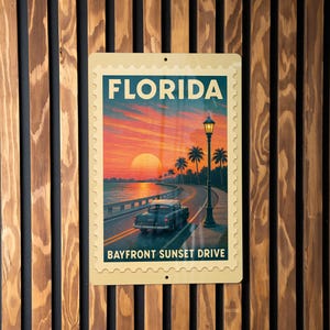 May include: A rectangular metal sign featuring a vintage Florida travel scene. The sign reads "FLORIDA" at the top and "BAYFRONT SUNSET DRIVE" at the bottom. The image depicts a sunset over a coastal road with a classic car.