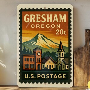 May include: A rectangular sign with a vintage design resembling a postage stamp. The sign features the text "Gresham Oregon 20c U.S. Postage" and an illustration of a mountain, buildings, and a church.