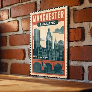 May include: A vintage-style metal sign featuring a stylized illustration of Manchester, England. The sign has a red border and the words "MANCHESTER ENGLAND" at the top. The illustration depicts buildings, a clock tower, and a bridge.