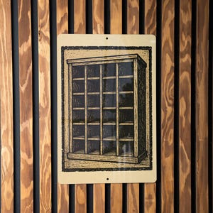 May include: A rectangular metal sign featuring a vintage illustration of a cabinet with multiple glass-paned doors. The sign is beige with a black border and is mounted on a wooden wall with vertical brown and black slats.