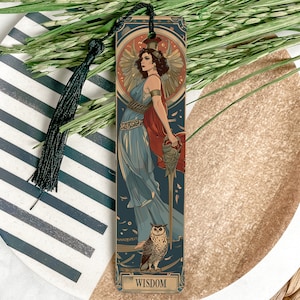 May include: A wooden bookmark with a vintage illustration of a woman in a blue dress holding a sword. The woman is surrounded by a halo of feathers. An owl is at her feet. The bookmark has the word "WISDOM" printed at the bottom.