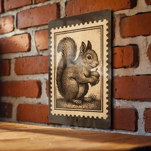 May include: A vintage-style metal sign featuring a detailed illustration of a squirrel holding an acorn. The artwork is framed within a postage stamp design, with a sepia-toned color palette. The sign is displayed against a red brick wall.