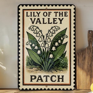 May include: Rectangular metal sign featuring a Lily of the Valley illustration. The sign has a cream-colored background with a black border and the words "LILY OF THE VALLEY PATCH" in black text. The image includes green leaves and white bell-shaped flowers.