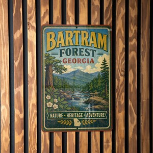 May include: A vintage-style metal sign for Bartram Forest, Georgia, featuring a scenic landscape with mountains, a river, and trees. The sign has a distressed look and the text "Nature, Heritage, Adventure".