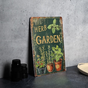 May include: A green metal sign with the text "HERB GARDEN" in gold lettering. The sign features a vintage style design with a distressed look. The sign depicts a variety of herbs in pots, including basil, rosemary, and thyme.