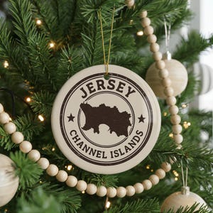 A Christmas tree decorated with ornaments, including a circular ornament with the text "Jersey Channel Islands" and a silhouette of the island.