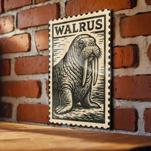 May include: A rectangular sign with a vintage stamp design featuring a walrus illustration. The word "WALRUS" is printed at the top. The walrus is depicted in black and white, with its tusks prominently displayed. The sign has a decorative border.