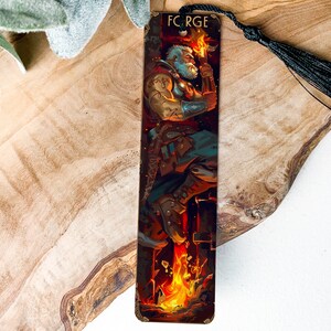 May include: A wooden bookmark with a black tassel. The bookmark features a colorful illustration of a bearded man standing in front of a fire, holding a torch. The text "FORGE" is printed at the top of the bookmark.