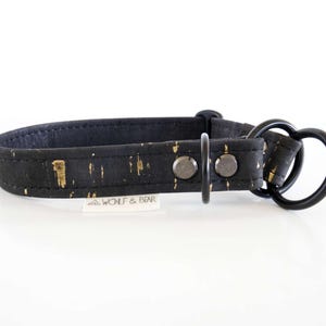 May include: Black dog collar with gold flecks and a black metal heart-shaped ring. The collar has a buckle and two rivets. The brand name "WOLF & BEAR" is printed on a small white tag.