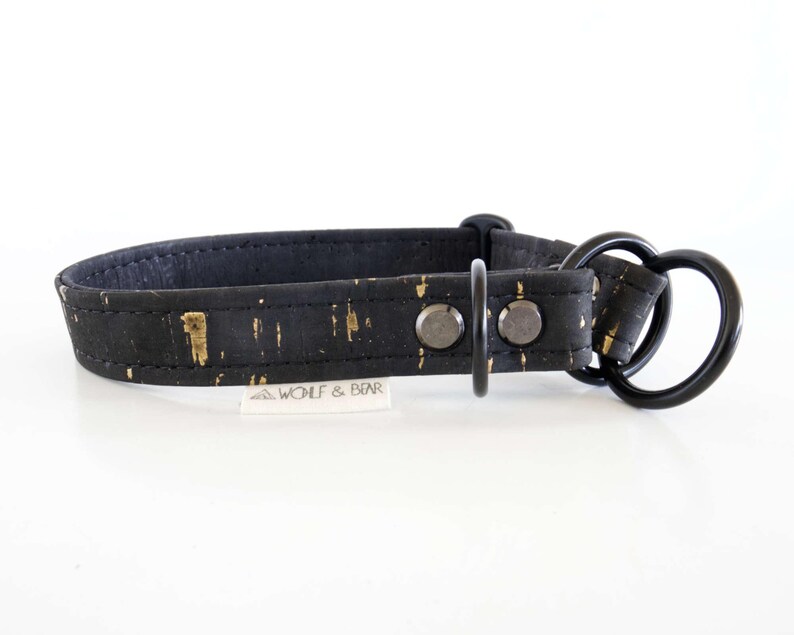 May include: Black dog collar with gold flecks and a black metal heart-shaped ring. The collar has a buckle and two rivets. The brand name "WOLF & BEAR" is printed on a small white tag.