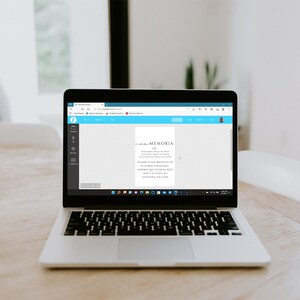 May include: A laptop computer displaying a web page with a document titled "Memoria De". The document contains text in Spanish. The laptop is on a wooden table.