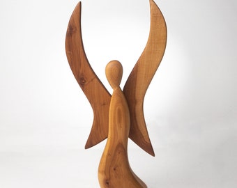 Puede incluir: Una escultura de madera de un ángel con las alas extendidas. El ángel está tallado en una sola pieza de madera y tiene un diseño simple y abstracto.