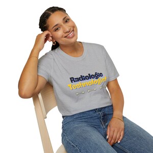 May include: A light grey t-shirt featuring the text "Radiologic Technologist" in black and yellow, with three bone graphics. The shirt is worn with blue denim jeans.