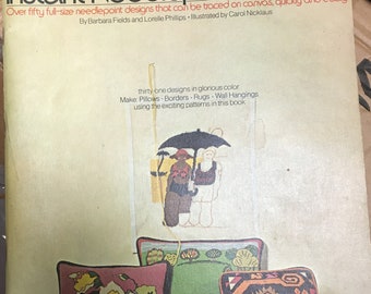 May include: A book cover with the title "Instant Needlepoint Designs" and a subtitle "Over fifty full-size needlepoint designs that can be traced on canvas, quickly and easily". The cover features a colorful illustration of needlepoint pillows with tassels.
