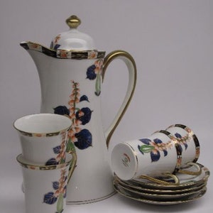 May include: A white porcelain coffee pot with gold trim and floral design, along with four matching cups and saucers.