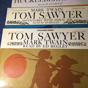 May include: Three vintage vinyl records featuring Mark Twain's classic novels: Huckleberry Finn, Tom Sawyer, and Tom Sawyer. Each record is labeled with the title of the book, the author's name, and the record label, Caedmon. The records are in a stack, with the top record showing a silhouette of two boys walking.