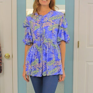 May include: A woman wearing a blue and pink floral print top with a tie at the front and blue jeans.