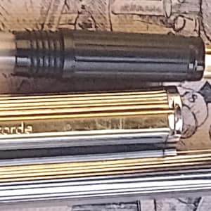 Puede incluir: Primer plano de una pluma estilográfica Concorde dorada y plateada. El bolígrafo tiene una sección de agarre negra y un plumín dorado. El cuerpo del bolígrafo es plateado con detalles dorados y la palabra "concorde" está impresa en el cuerpo.