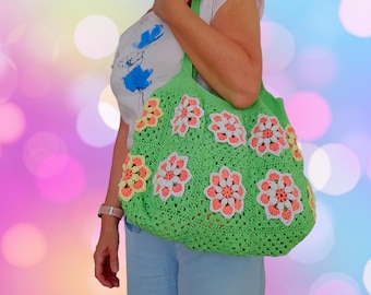 May include: A green crocheted tote bag with colorful flower designs. The bag has a wide, open top and is made with a thick, textured yarn.
