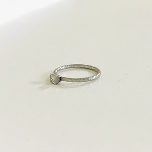 May include: A silver ring with a square-shaped clear stone set in the band. The band is textured and has a hammered finish.