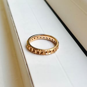 May include: A gold band ring with a geometric design and the inscription "Tiffany & Co. AG 925 ITALY".