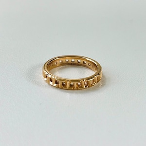 May include: A gold band ring with a repeating pattern of squares and diamonds. The ring is inscribed with "Tiffany & Co. 1837"