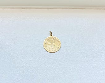 May include: A gold-colored Sagittarius pendant. The round pendant features an engraved archer with the text "SAGITTARIUS" and the dates "NOV 22 - DEC 21". The pendant has a small loop at the top for a chain.
