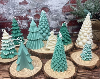 May include: Assortment of green and white Christmas tree candles on wooden slices. The candles are decorated with different textures and designs.