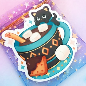 May include: A sticker featuring a cartoon illustration of a blue mug with a black cat perched on the rim. The mug is filled with hot chocolate and marshmallows, and a brown spoon is sticking out of the top. A brown and orange cookie is sitting next to the mug.