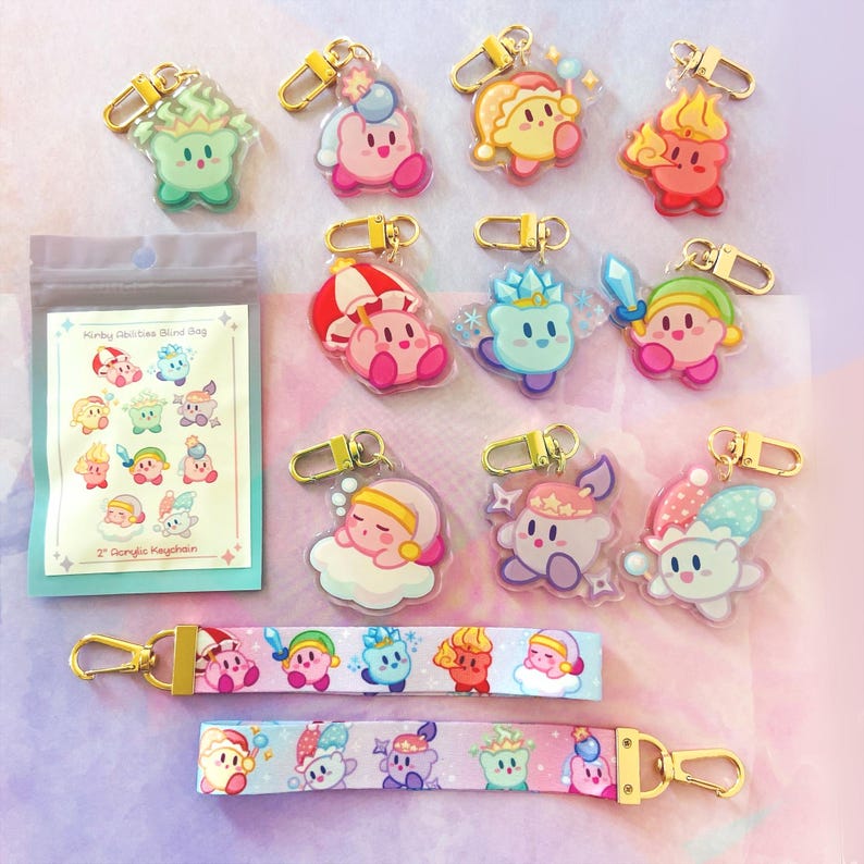 May include: A collection of colorful acrylic keychains featuring various character designs. The keychains have gold-colored clasps. Also included are two matching lanyards and a blind bag with the text "Kirby Abilities Blind Bag" and "2" Acrylic Keychain".