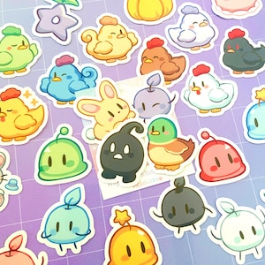 May include: A collection of colorful cartoon stickers featuring various cute creatures. The stickers include chicks, ducks, bunnies, and other whimsical characters in shades of yellow, blue, green, and red. The stickers are arranged on a purple and white background.