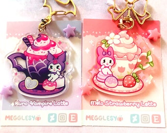 May include: Two acrylic keychains on display cards. The left features a purple cup with a bat-shaped handle, a character, and the text Kuro Vampire Latte. The right features a pink cup with a flower, a character, and the text Melo Strawberry Latte.