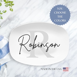 Może przedstawiać: Biała owalna tacka do serwowania z szarym literą R i nazwą Robinson w czarnym piśmie. Tekst "You Choose The Colors" znajduje się na niebieskiej naklejce w kształcie gwiazdy. Tekst "Made in the USA" znajduje się na dole tacy z małą flagą amerykańską.