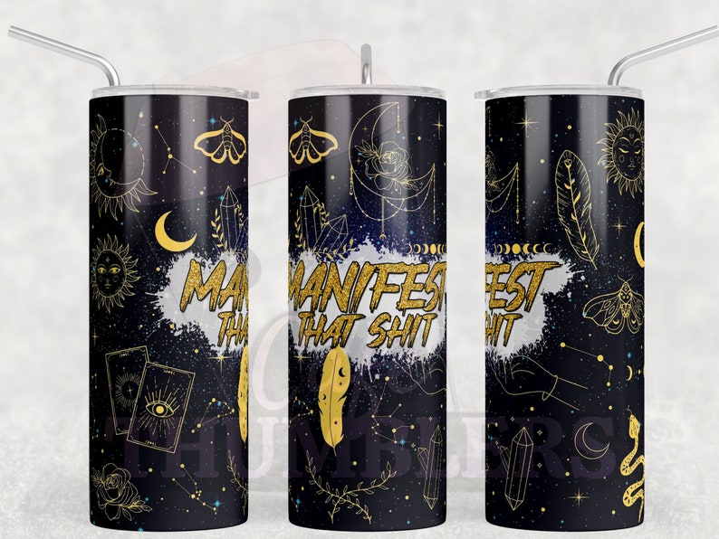 Pode incluir: Um copo preto e dourado com um design celestial. O copo apresenta ilustra&ccedil;&otilde;es douradas do sol, da lua, das estrelas, dos cristais e das mariposas. As palavras "MANIFEST THAT SHIT" s&atilde;o impressas em dourado sobre um fundo branco salpicado.