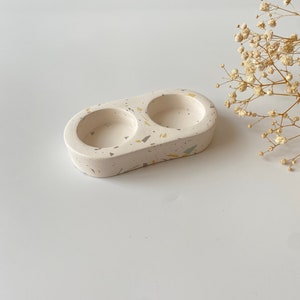 Pode incluir: Prato duplo de cer&acirc;mica branca com um padr&atilde;o de terrazzo salpicado em tons de amarelo, verde e cinza. O prato &eacute; ideal para guardar objetos pequenos como joias ou chaves.