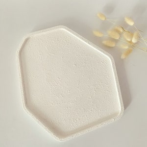 May include: White octagonal tray with a textured surface. The tray is made of a smooth, white material and has a slightly raised edge.