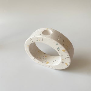 Pode incluir: Vaso de cer&acirc;mica branco com um padr&atilde;o de terrazzo salpicado em tons de amarelo e verde. O vaso tem uma abertura redonda na parte superior.