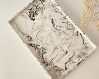 May include: A white rectangular tray with a black marbled design. The tray is made of a smooth, durable material and is perfect for serving snacks, drinks, or other items.